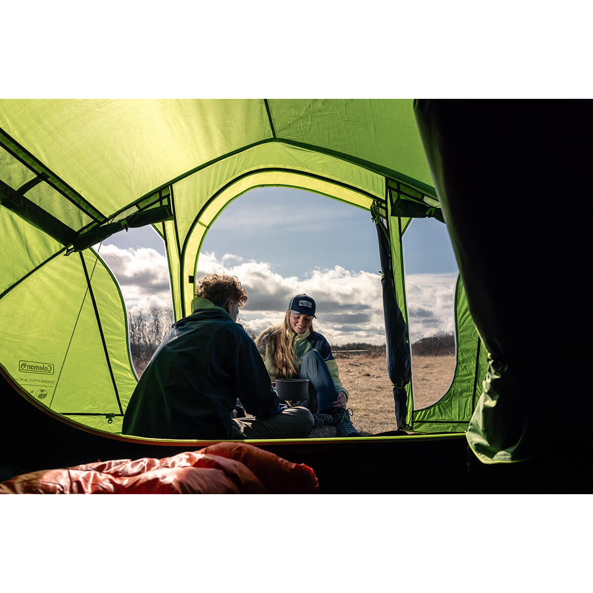 View from inside the bedroom - couple either side of a cookpot setup with one inside the tent, one out