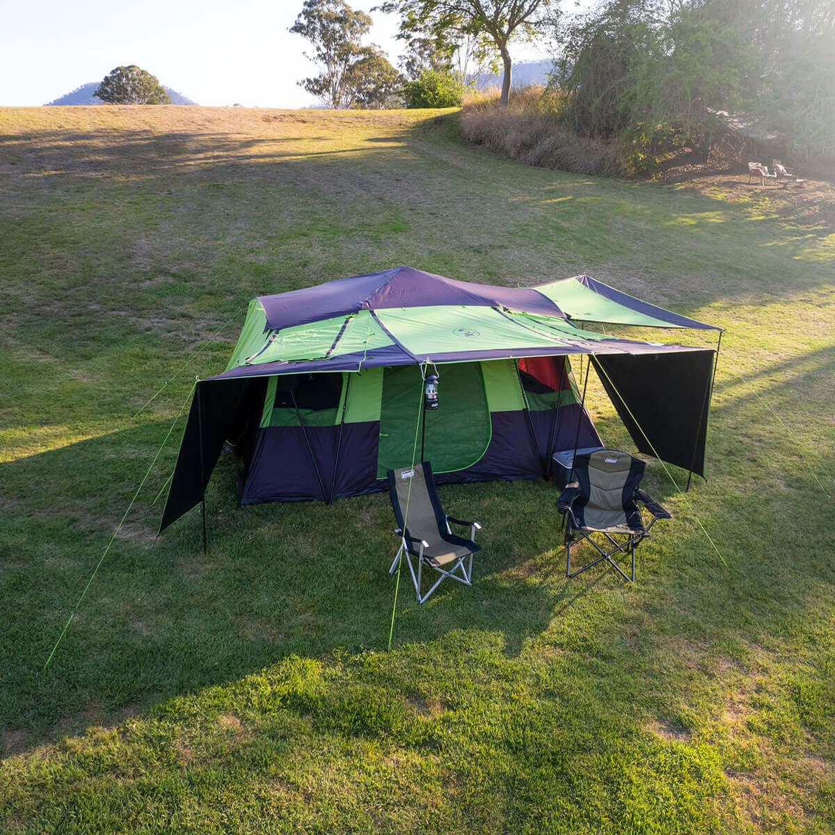 3/4 top view of tent pitched at campsite, couple of chairs under front awning