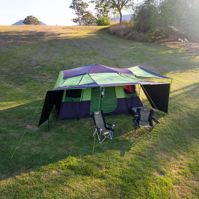 3/4 top view of tent pitched at campsite, couple of chairs under front awning