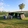Pitched at a campsite with all awnings and sunwalls up, group of 4 playing cards at a table in front of the tent