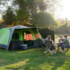 Pitched at a campsite with awning and sunwalls up, group of 4 playing cards at a table in front of the tent