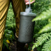 Close up of Mammoth Grey, carried by the carry handle in bush setting