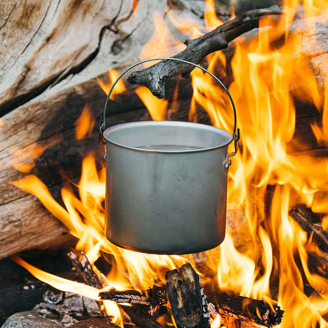 Billy hanging from branch hanging over a camp fire to boil water (no lid)