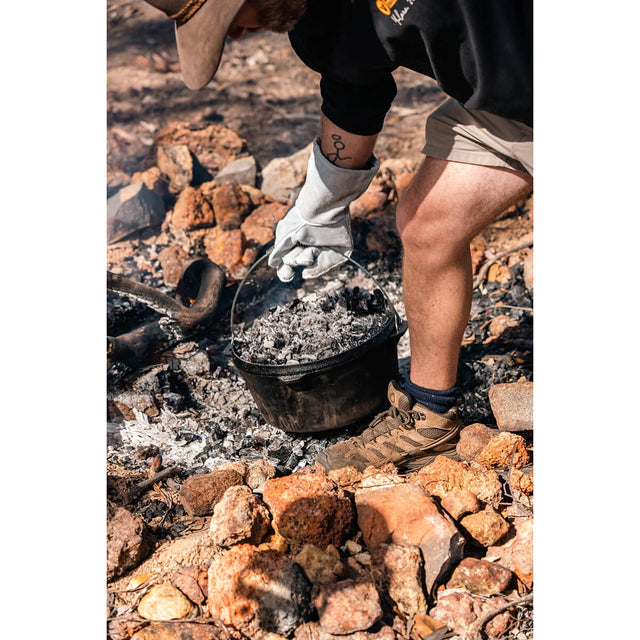 In use with embers on top and being lifter by gloved hand