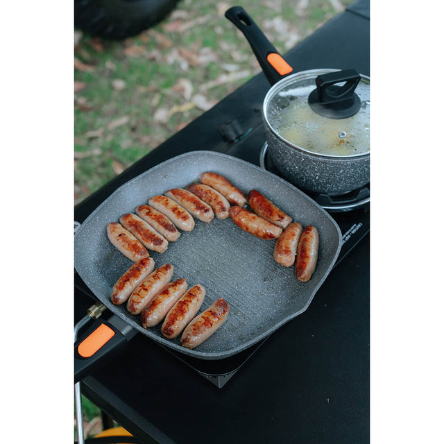 In use cooking sausages on a stove in the outdoors