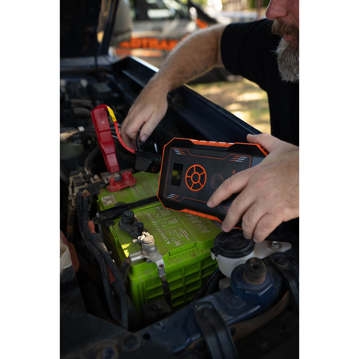 Jumper cable clamps being attached to vehicle battery