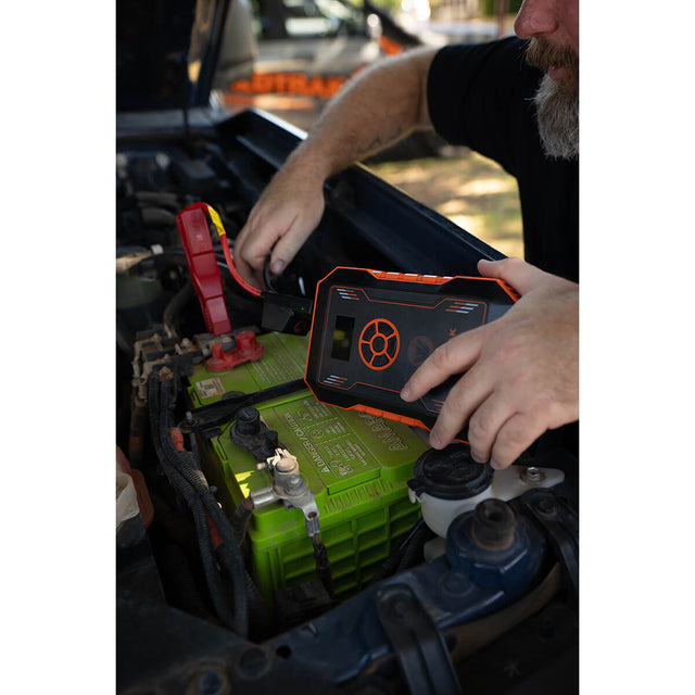 Jumper cable clamps being attached to vehicle battery