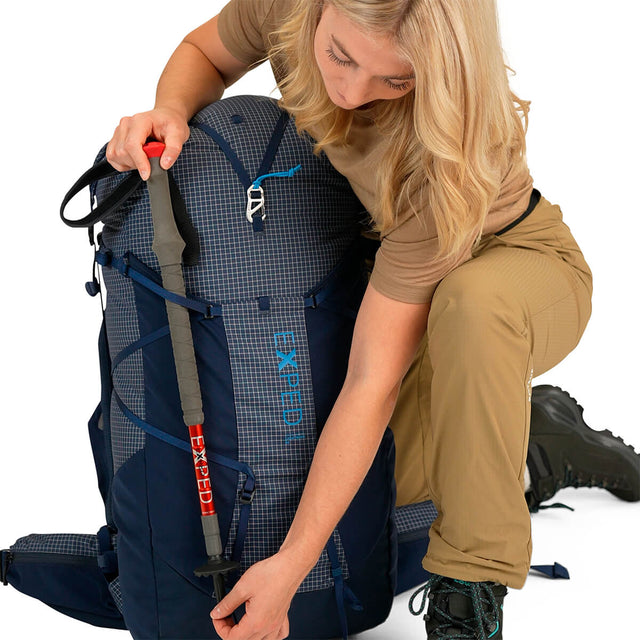 Navy 60L using compression straps and lower loop to stow trekking pole