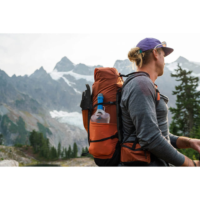 Filled system in side pocket of a pack on a trampers back in the mountains